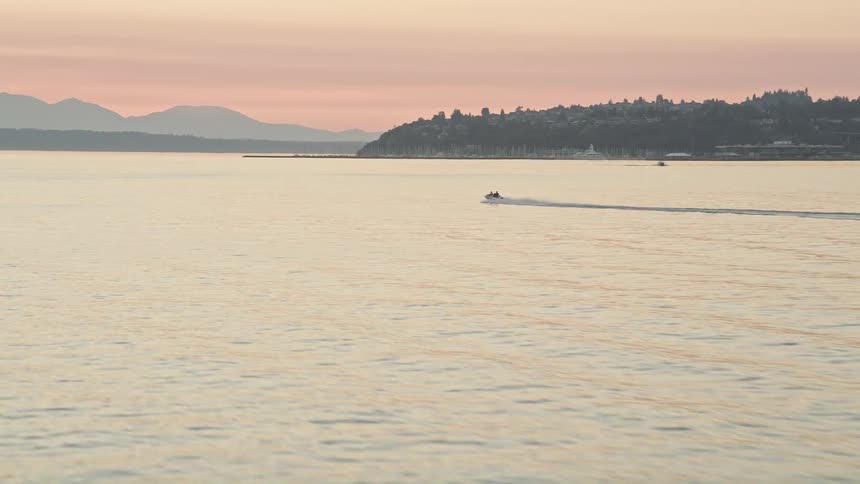 Aerial footage of a speedboat being tracked as it cruises across Elliott Bay at sunset in Seattle Washington showcasing water sports and recreation on the bay