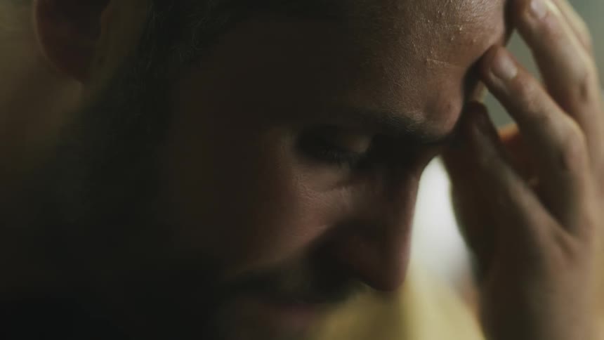 Frowning man touches his forehead