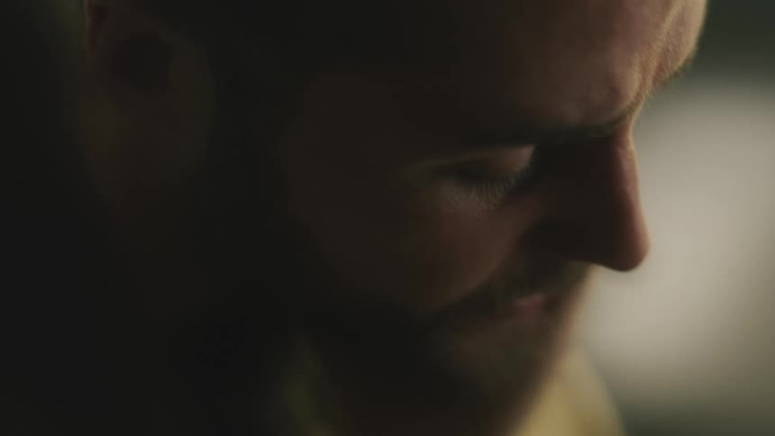 Close up of the face of a sad bearded man rubbing his face