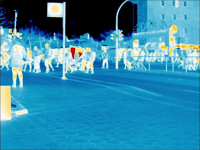 A crowd crosses the street at a busy intersection