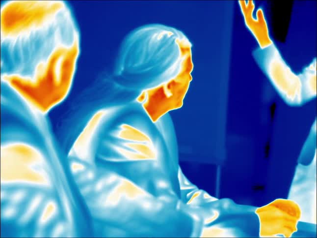 A heat vision view of two elderly men sitting and talking with a third person