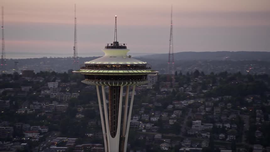 Drone aerial view of the iconic Space Needle in downtown Seattle Washington during a stunning sunset with the city below and rivers throughout