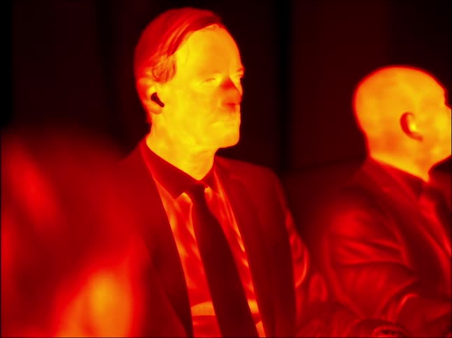Two men sitting around filmed with an infrared camera