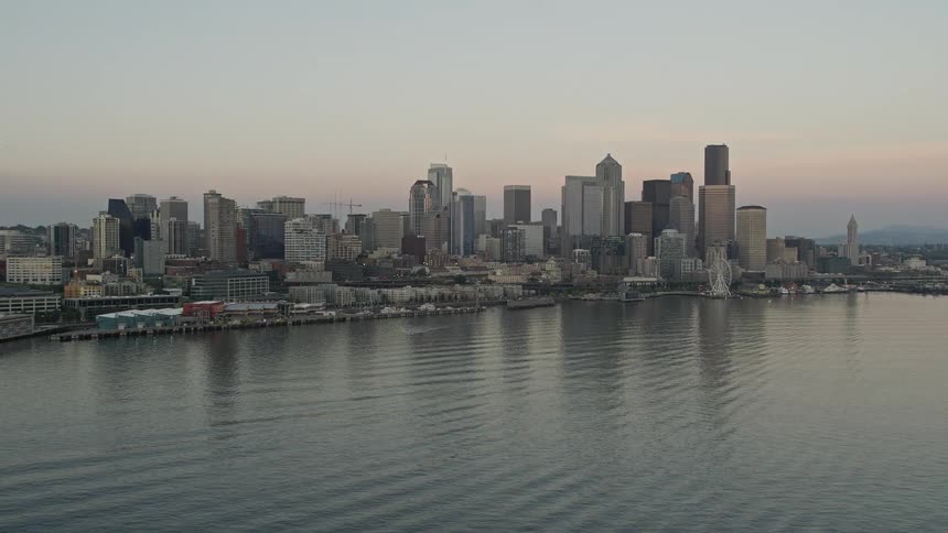  aerial footage showcases the iconic Space Needle skyscrapers and Central Waterfront piers in Downtown Seattle Washington during a vibrant sunset