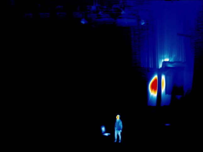 Man stands from chair outdoors in infrared image