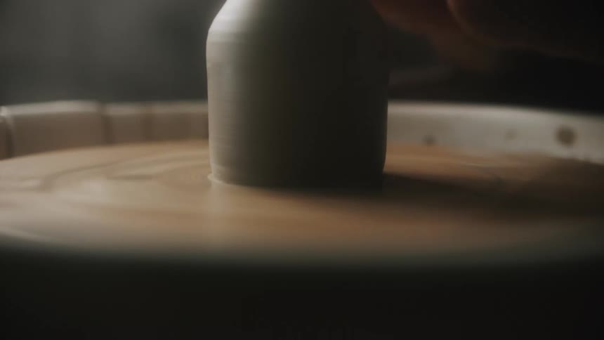 A person creates a vase on a pottery wheel