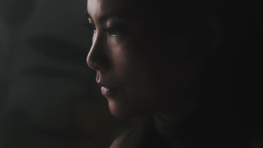 Close up of the face of a young beautiful asian woman inside a dimly lit room