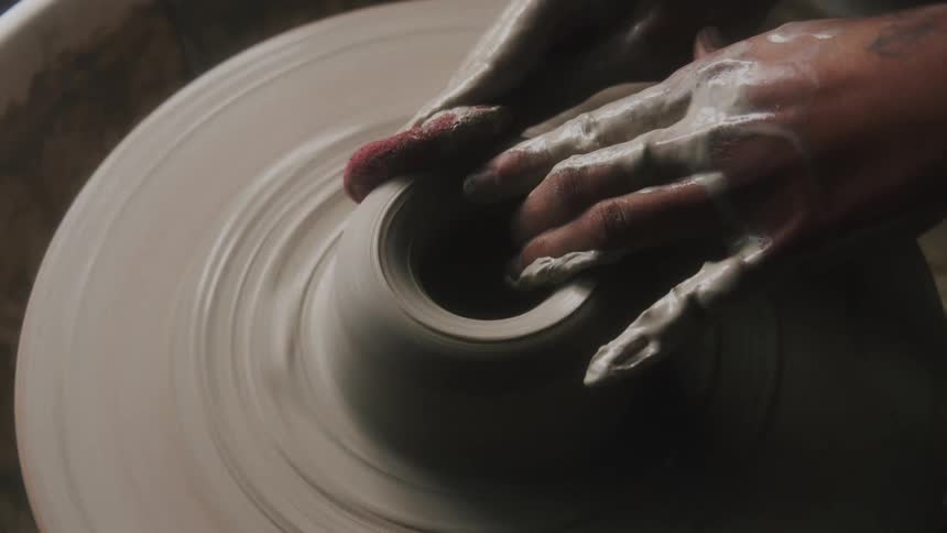 A woman creates a vase on a pottery wheel