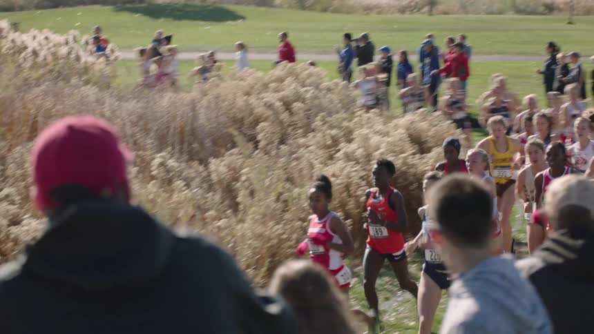 Teen girls compete in a track meet on a dirt trail