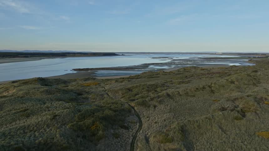 A trail runs through rolling hills along a river