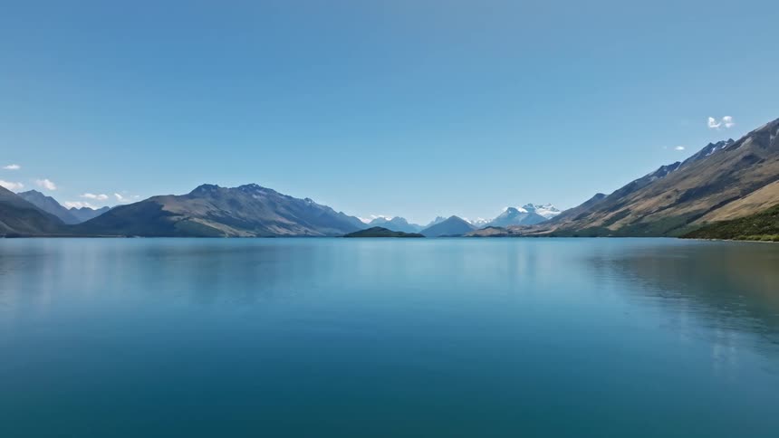 Lake reflects mountains under a calm blue sky