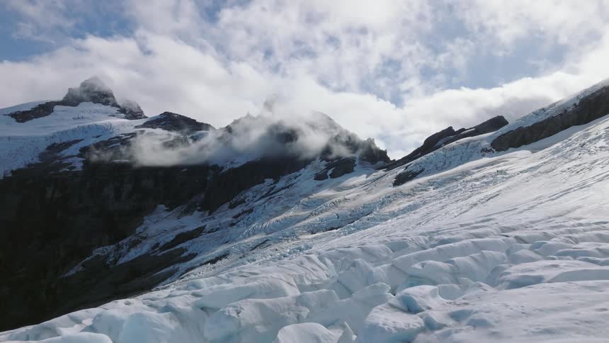 Dense snow and ice covered glacier with alpine peaks