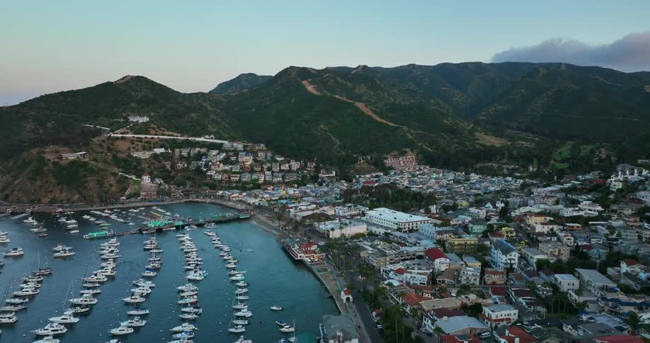 Aerial view of rows of boats moored on a bay in front of a coastal town at morning