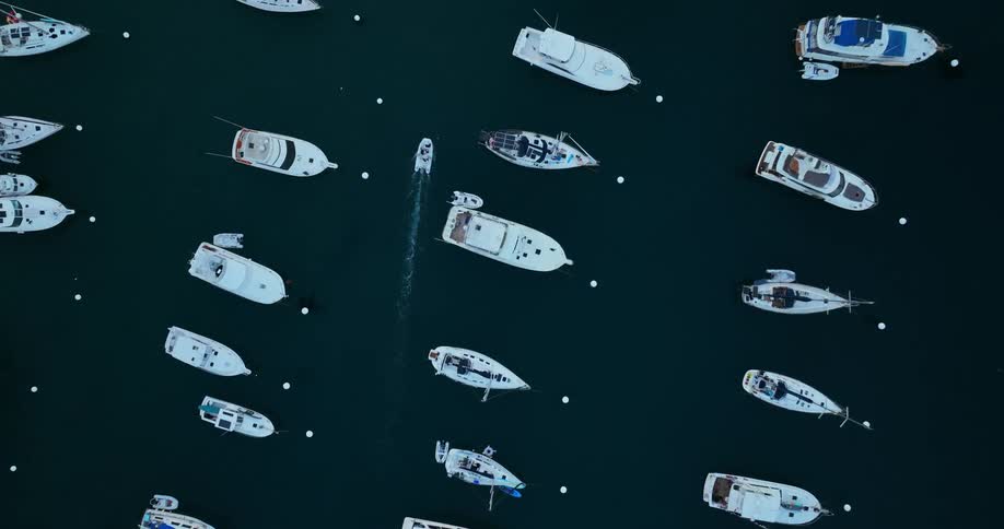 Aerial view of a boat traveling through an area filled with other boats and sailboats