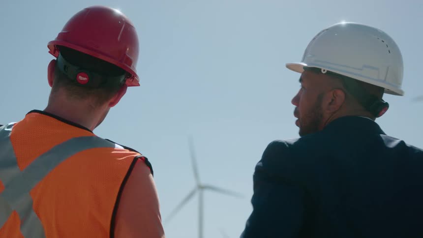 Two workers talk by the wind farm
