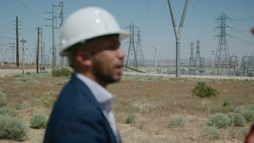 Two colleagues chat while standing outside a wind farm