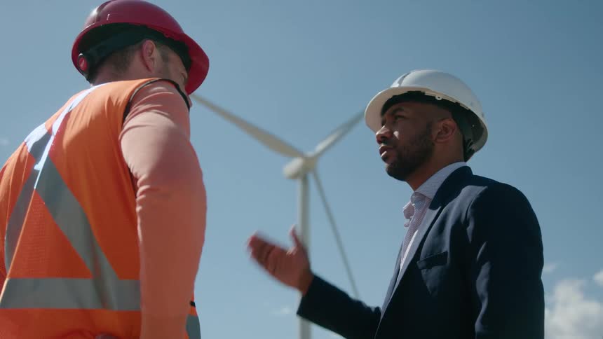 An engineer speaks with a worker about wind turbines