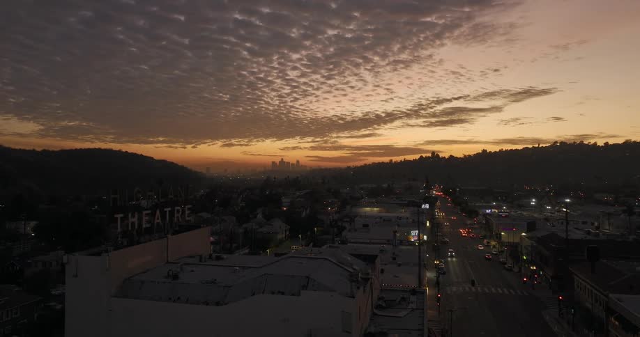 Traffic moves down street leading through town to red tinted sky