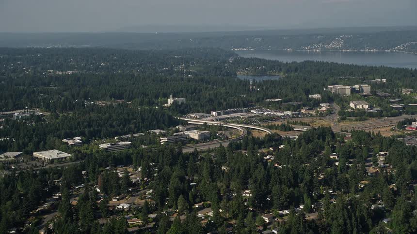 Aerial view of office buildings and the Seattle Washington Temple in Bellevue Washington surrounded by lush woods and bathed in sunlight