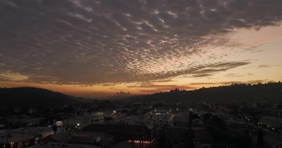 Aerial view of distant skyline skyscrapers and buildings against the cloudy sky at dusk