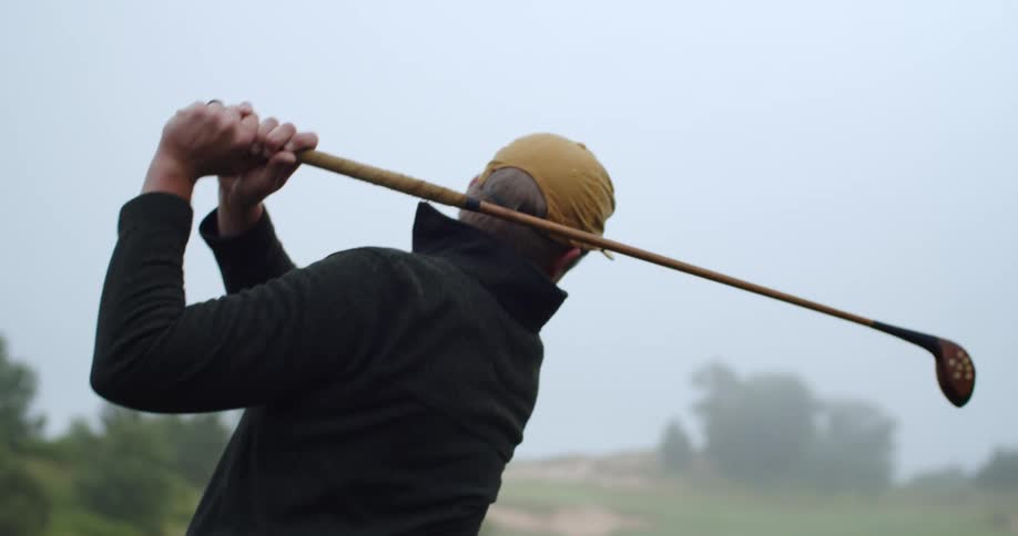 A man is golfing outdoors during the spring time