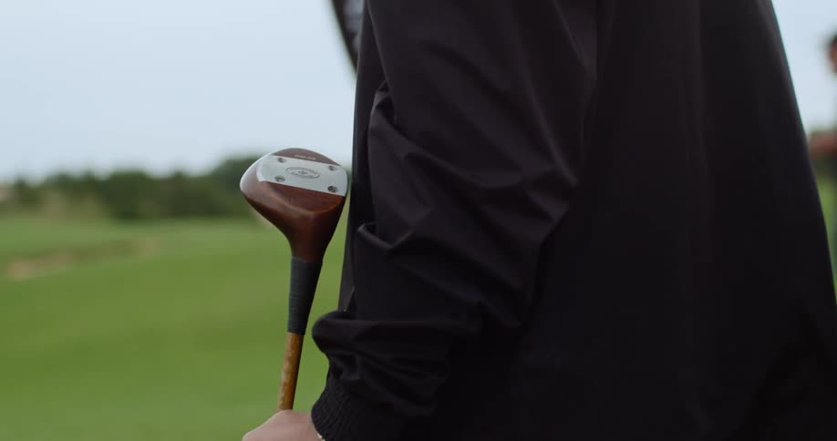 Aman holding the head of golf club as he studies the course