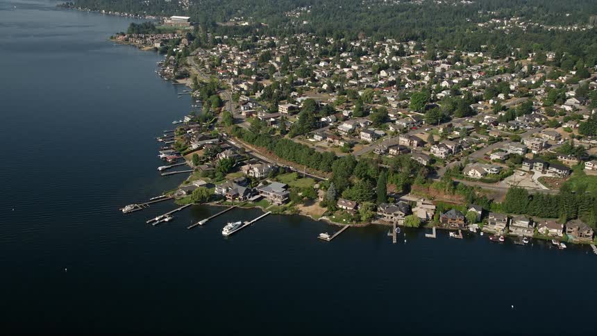 Approach and tilt down to lakeside homes and docks on Lake Washington in Kennydale Renton Washington on a sunny day