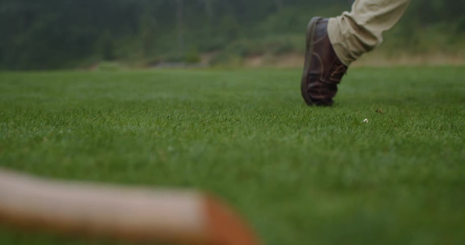 A golfers foot twists as they swing a club and strike a golf ball