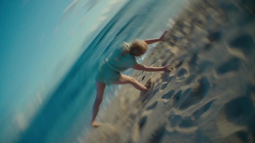 Girl with braids t shirt and shorts does a cartwheel on the beach near the ocean