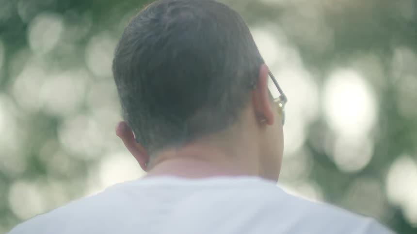 A man sits in front of trees