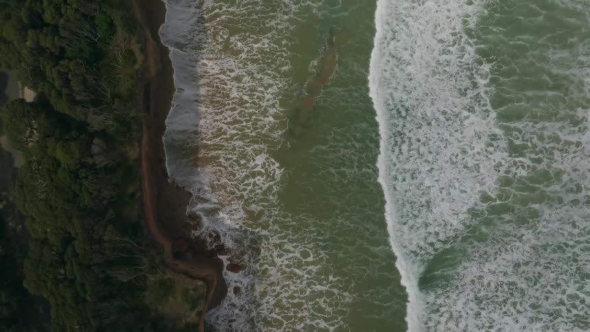 Waves crash onto the shore below a coastal neighborhood