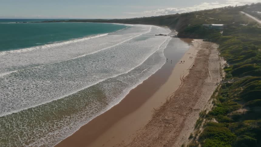 Aerial view of ocean waves breaking against the beach at the bay