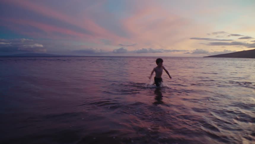 A boy runs to his mother from the water