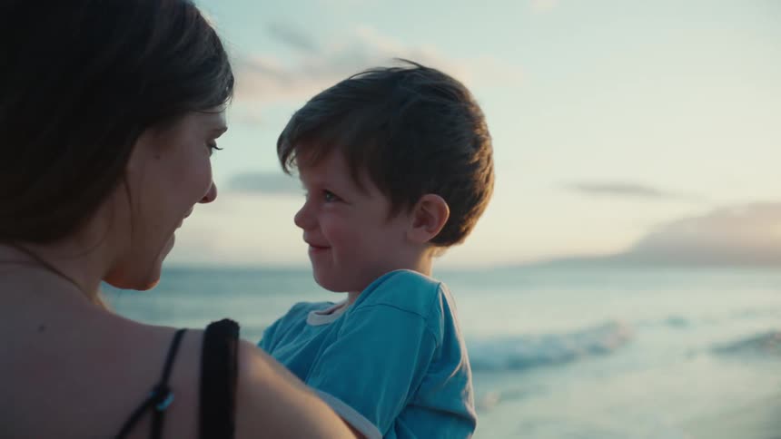 A mother holds her child on the beach