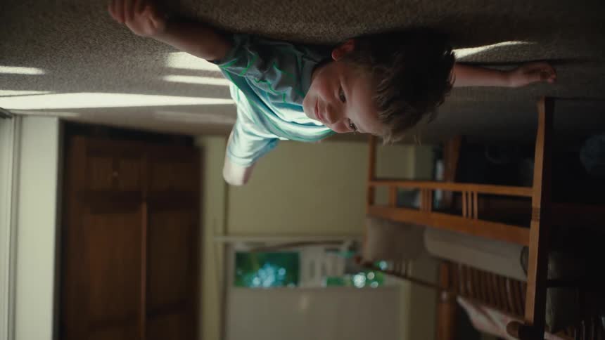 Boy lies against carpeted floor with shot angled upside down