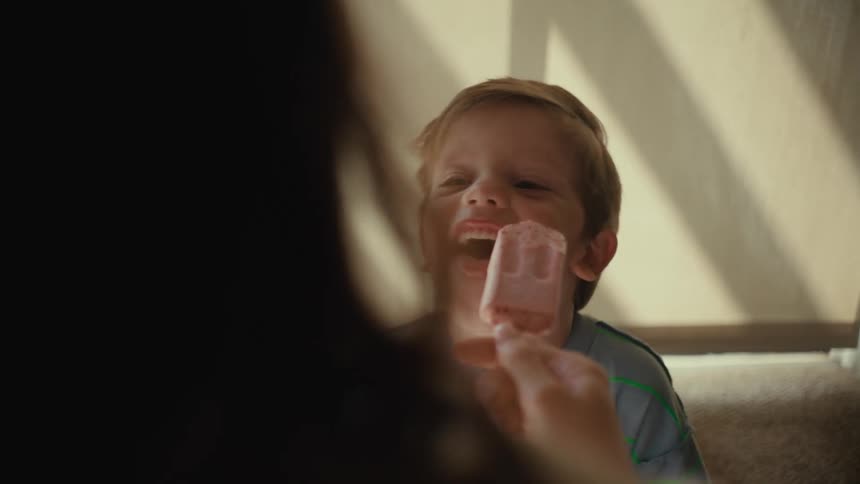 Mother and son sharing a popsicle and laughing