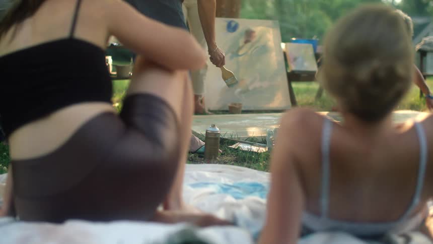 Women watch a painting demonstration in the park