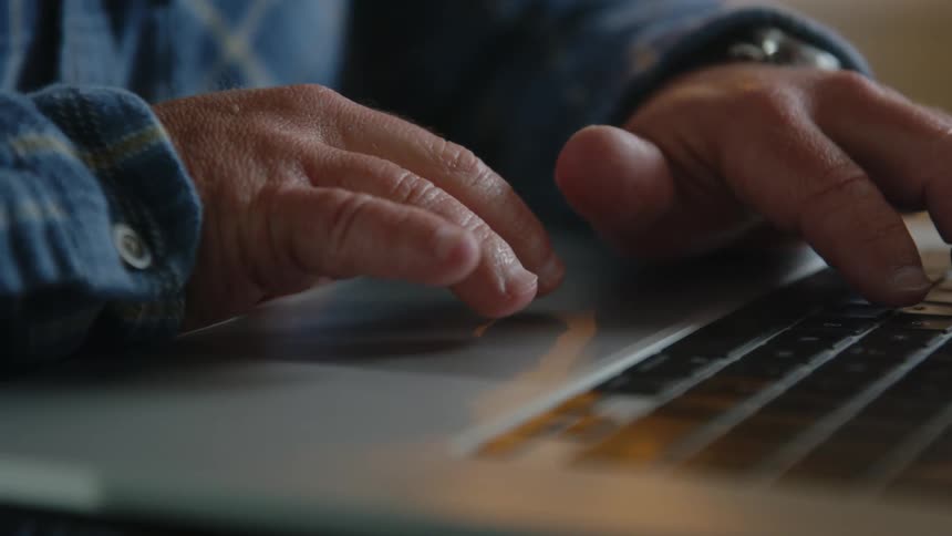 Person with small hands types on laptop keyboard and uses touch pad