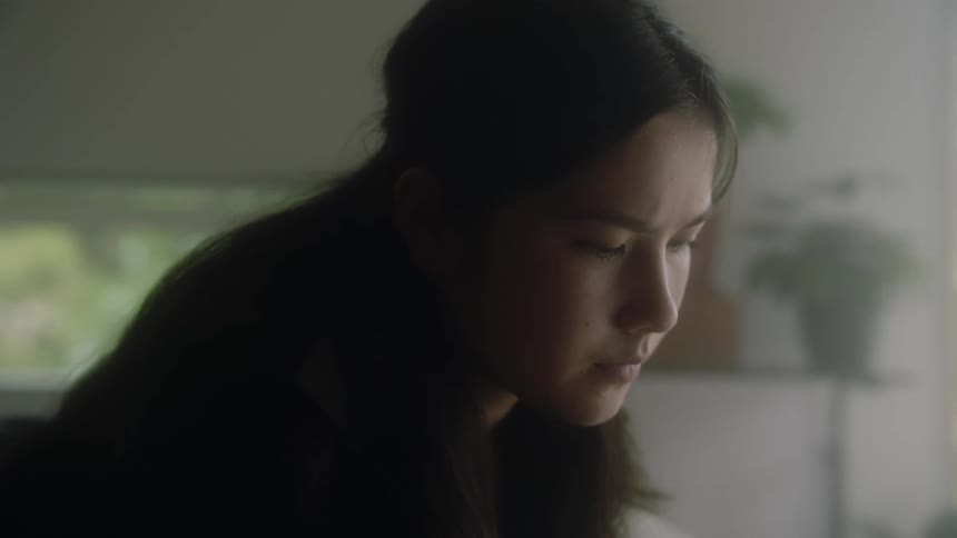 A young woman sits in a room at home