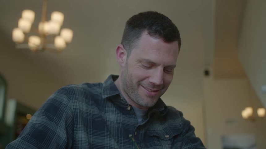 Man smiles and looks up while using pencil