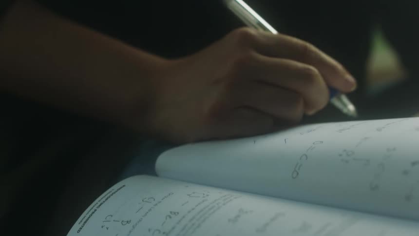 A student is using a pen to complete math homework in a textbook