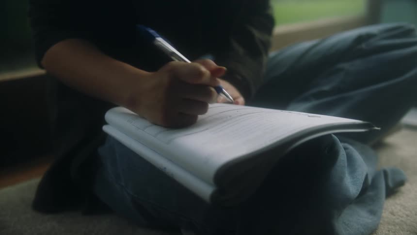 A person is writing in their notebook