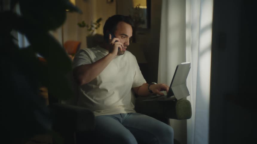 A man talks on his phone while using his tablet