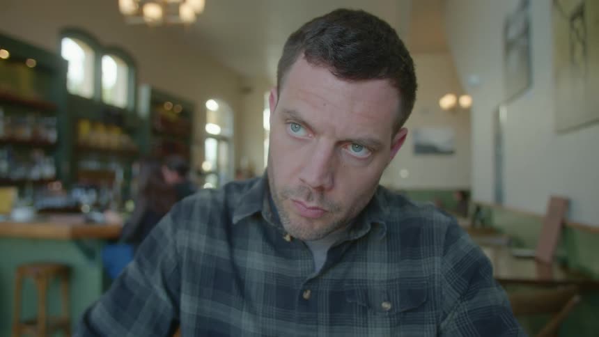 Man sits at table in restaurant using pencil