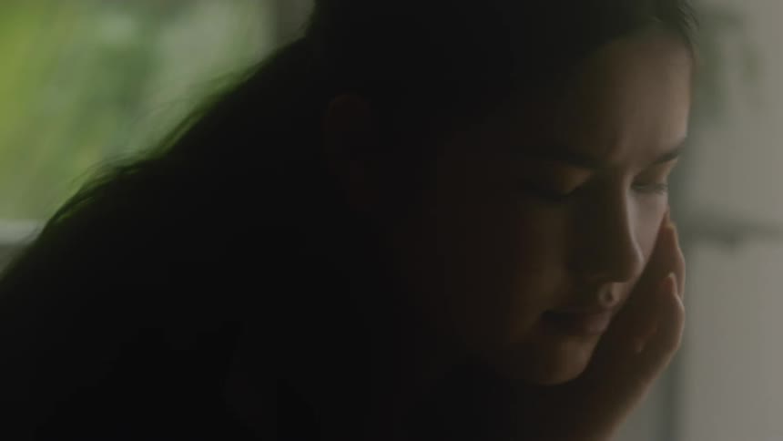 A teenage girl is sitting and concentrating on something in front of her