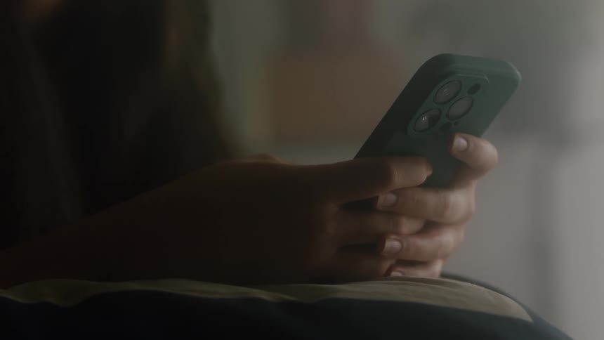 Woman leans against pillow and scrolls on smartphone