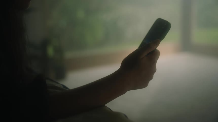 A girl scrolls on a smartphone in her home