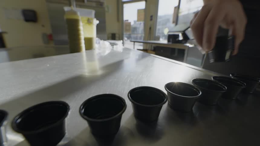 Restaurant worker places small cups on counter during prep