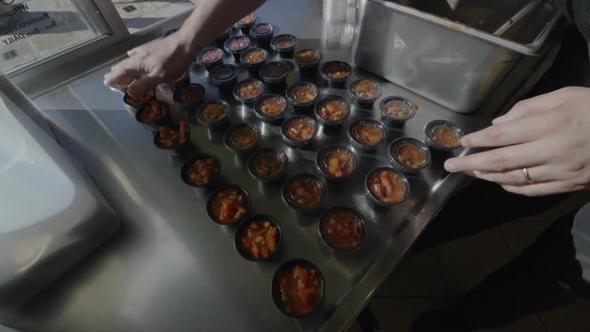 An employee closes the lids on the cups of food