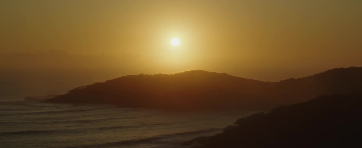 A captivating sunset scene near a hill overlooking the ocean